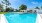 Large sparkling blue pool with a large pool deck and lounge chairs